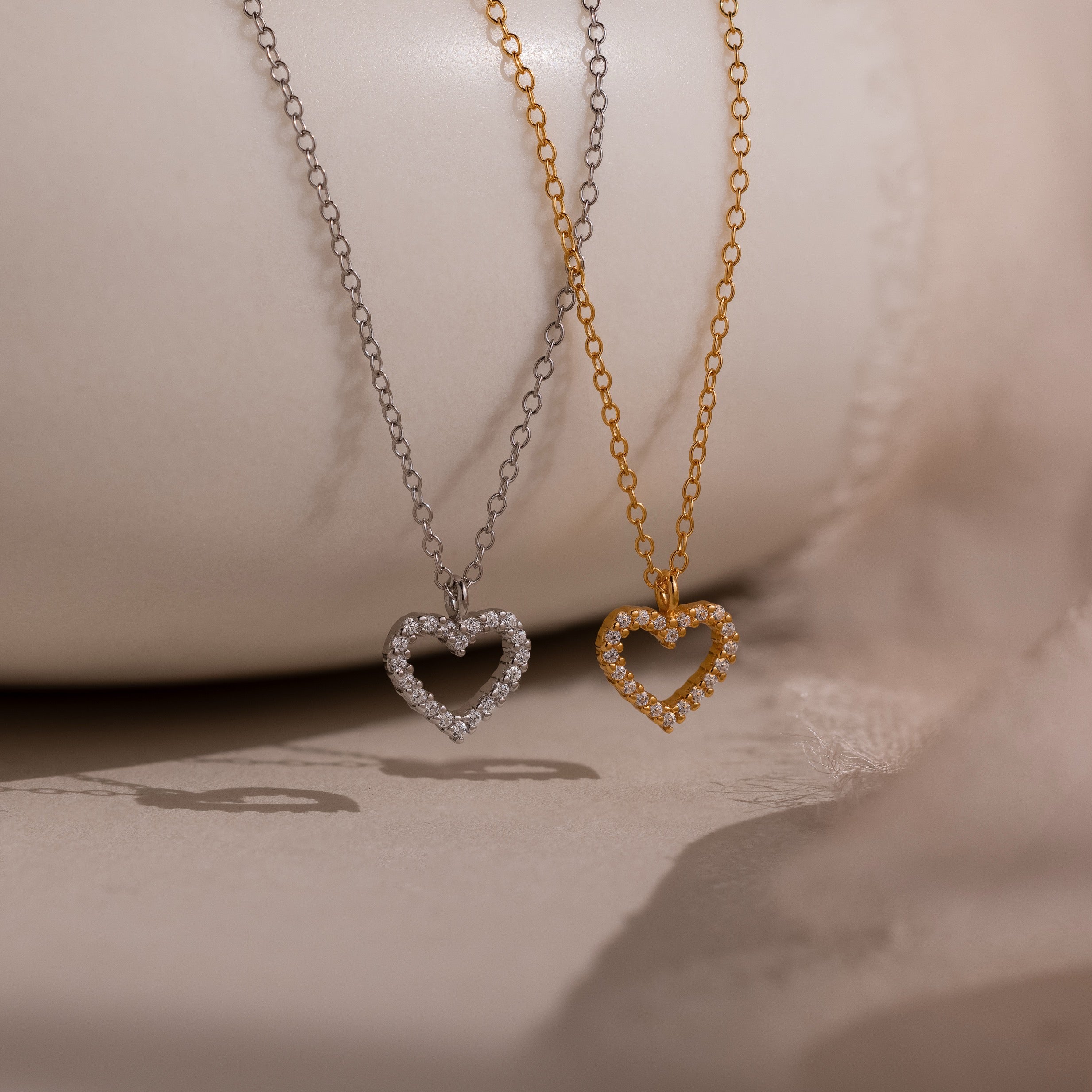The Forever Pave Heart Necklaces are shown with two heart-shaped pendants—one silver, one gold—with sparkling stones, perfect for bridal jewelry or special occasions.