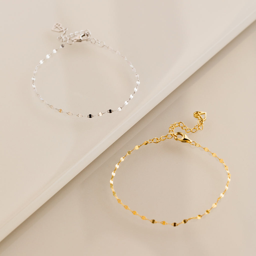 The Josephine Chain Bracelet in Sterling Silver is elegantly displayed on a neutral beige surface.