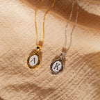 Initial Pendant Necklace in Gold with the letter A and White Gold with the letter K in a vintage serif font lay side by side.