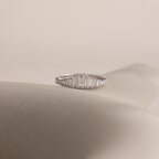 The Art Deco Diamond Ring in Sterling Silver features baguette-cut clear stones in a chandelier-inspired design, elegantly displayed on a soft, neutral background.