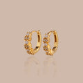 Pair of small gold huggie hoops with radiant diamond clusters.
