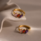 Multiple Tapered Birthstone Huggies in 18K Gold with pink, red, and purple rectangular stones displayed on a white sculpted surface—ideal for fans of modern statement jewelry or unique Art Deco-inspired earrings.