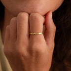 A hand with a Diamond Morse Code Ring in Rose Gold, featuring small gemstones, held near the person's lips.