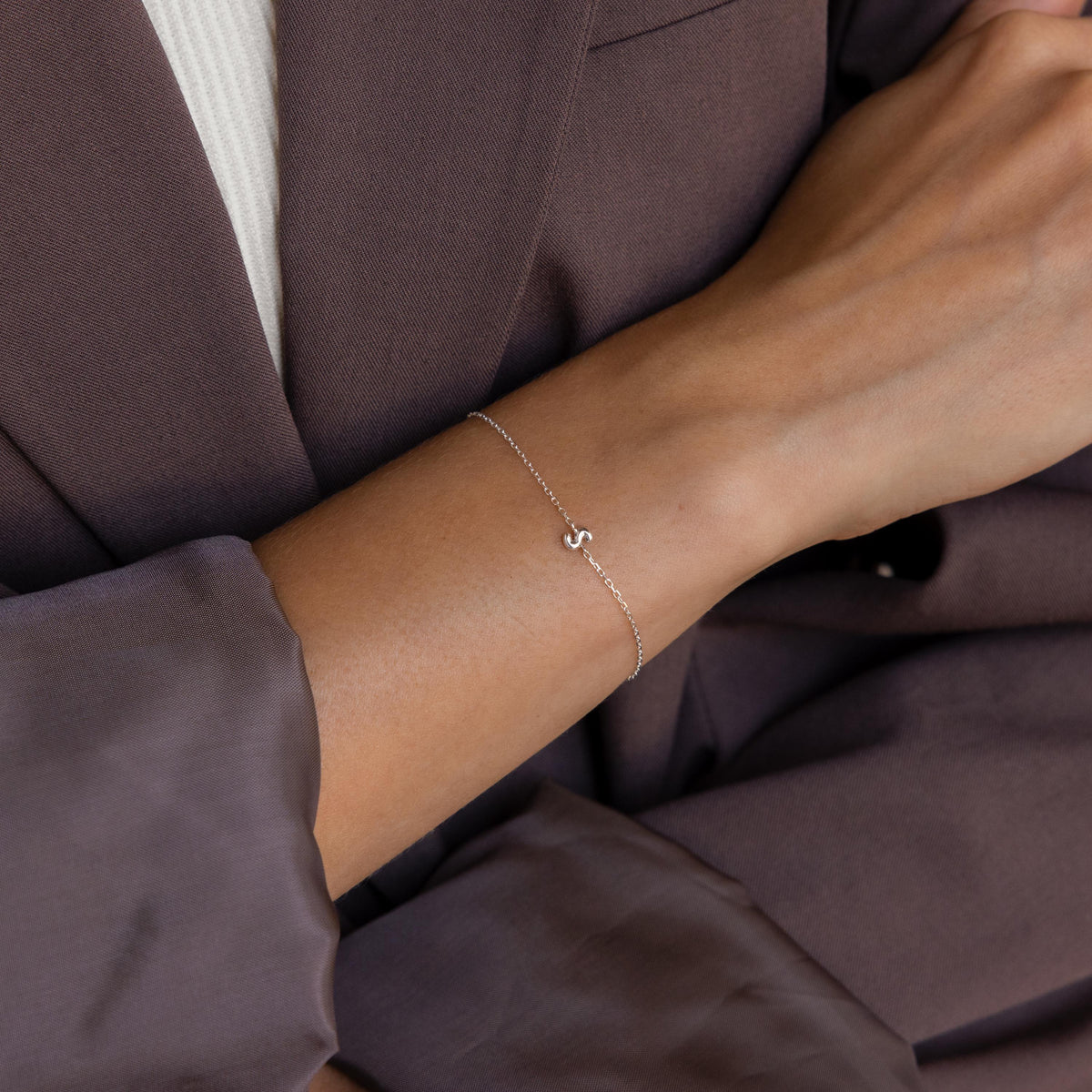 Model wearing a dainty silver 3D bubble initial S bracelet.