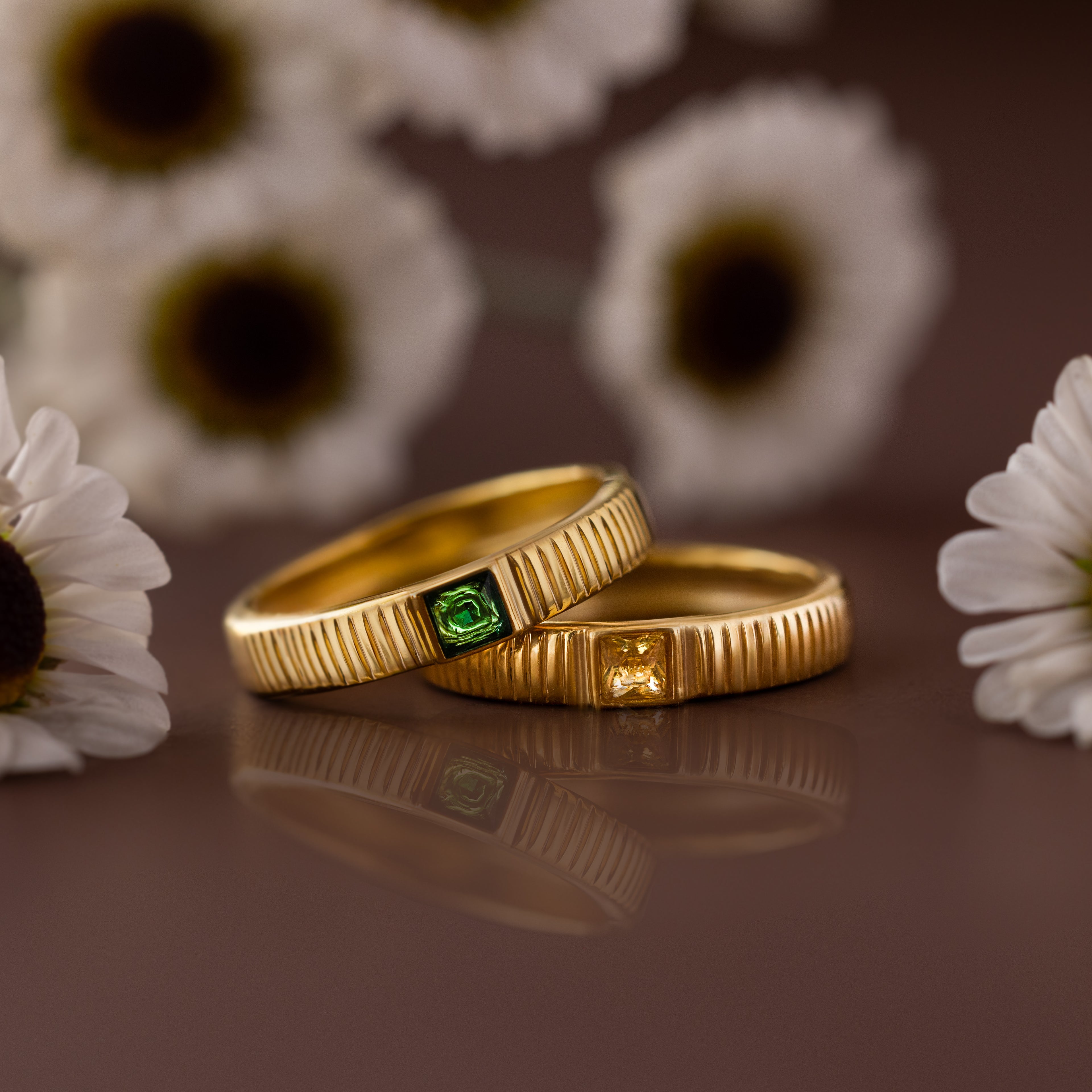 A Ribbed Topaz Band with a square-cut yellow stone, set in a ribbed gold band, is displayed among white daisies.