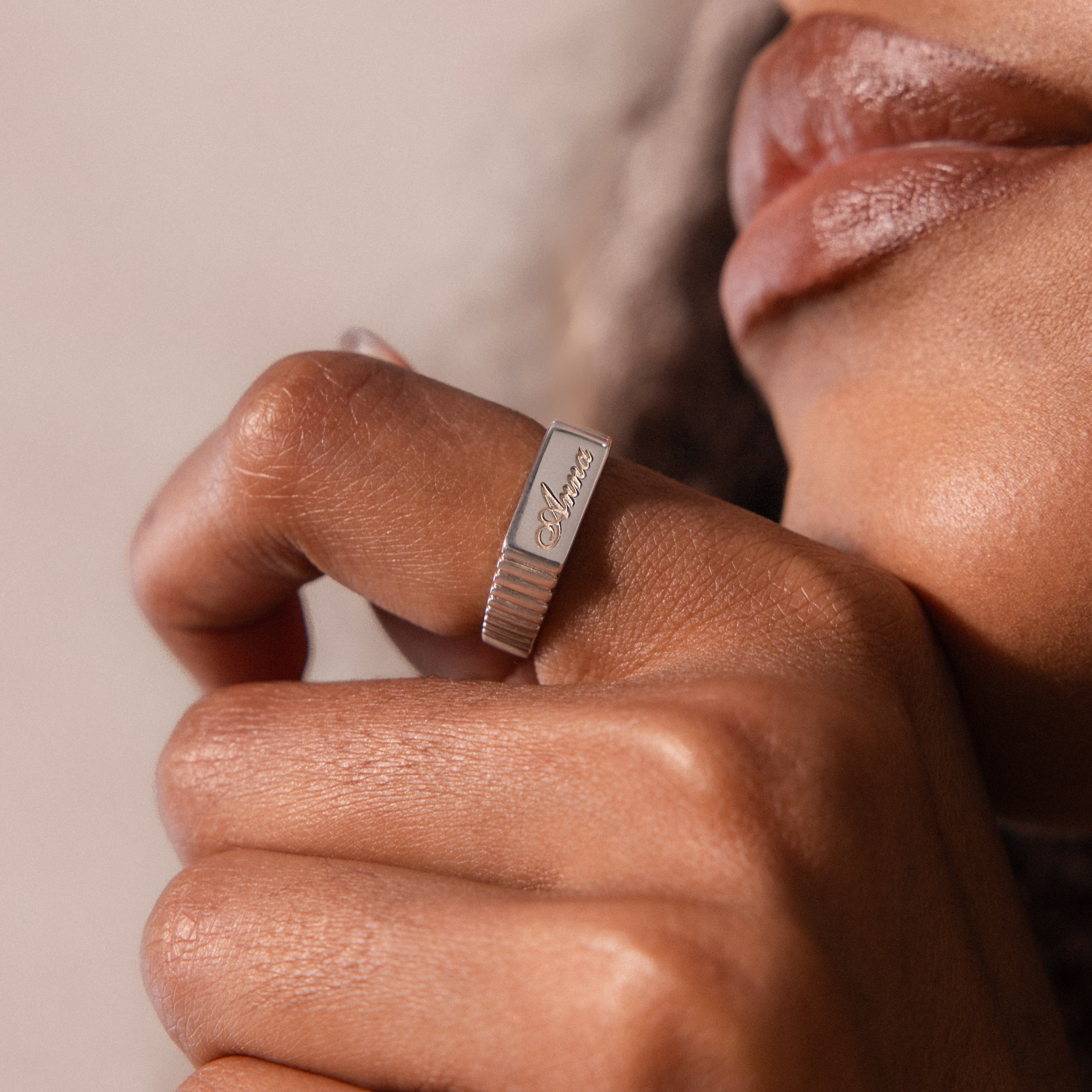 Close-up of a hand wearing the Ribbed Name Signet Ring in Silver, personalized with "fearless," held near the lips.
