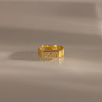A Ribbed Name Signet Ring engraved with “victor” and “Leah” rests on a smooth, light surface.