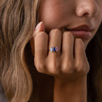 A woman with wavy hair rests her chin on her hand, showcasing the Multiple Marquise Birthstone Ring featuring blue, purple, and pink stones.