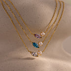 The Marquise Birthstone & Pearl Necklace is elegantly displayed on a beige mannequin bust.