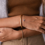 Close-up of crossed arms wearing the Toi et Moi Teardrop Heart Bracelet over a brown ribbed top and beige pants.
