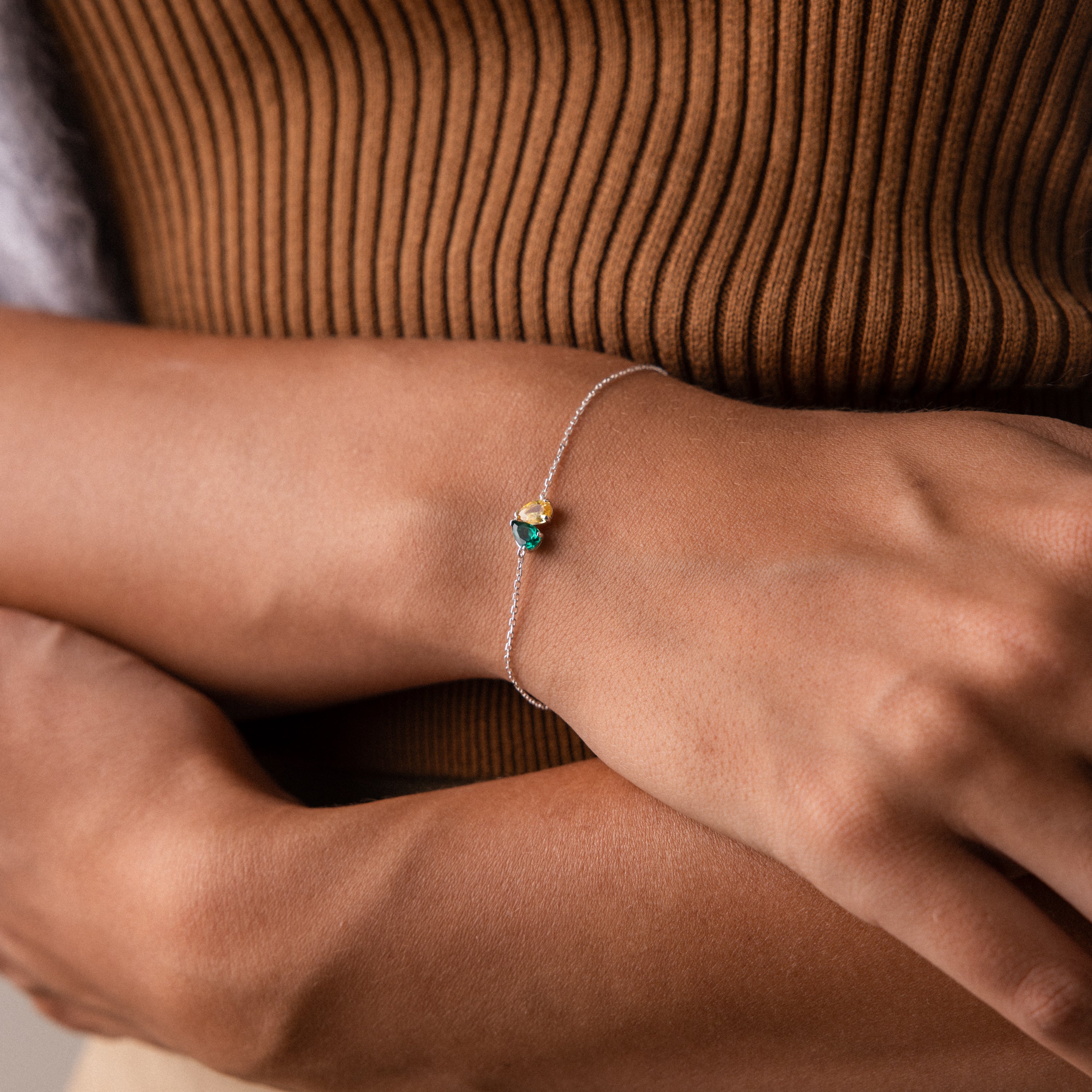 A woman wears the Toi et Moi Teardrop Heart Bracelet in Sterling Silver, elegantly paired with a ribbed brown top.