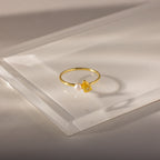 The Teardrop Topaz & Pearl Ring, featuring a yellow topaz and a white pearl, sits on a translucent surface, highlighting elegant jewelry perfect for any occasion.