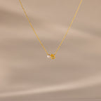 The Teardrop Topaz & Pearl Necklace features a gold chain with a small pearl and yellow topaz teardrop pendant, beautifully displayed on a neutral background—a timeless gift for any occasion.
