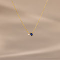 Teardrop Sapphire & Pearl Necklace with a gold chain, featuring a blue sapphire and a delicate pearl on a soft beige background—a timeless gift for any occasion.
