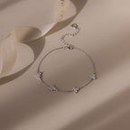 Silver bracelet with diamond floral charms on a beige background