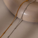Two gold and silver beaded bracelets on a beige surface