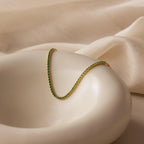 Classic Birthstone Tennis Bracelet showcased on a smooth white dish against a soft beige fabric background, ideal for pairing with a gold necklace or other personalized jewelry.