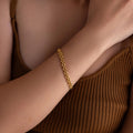 A Strap Bracelet graces a woman's wrist, paired with a brown ribbed tank top—a true statement piece.