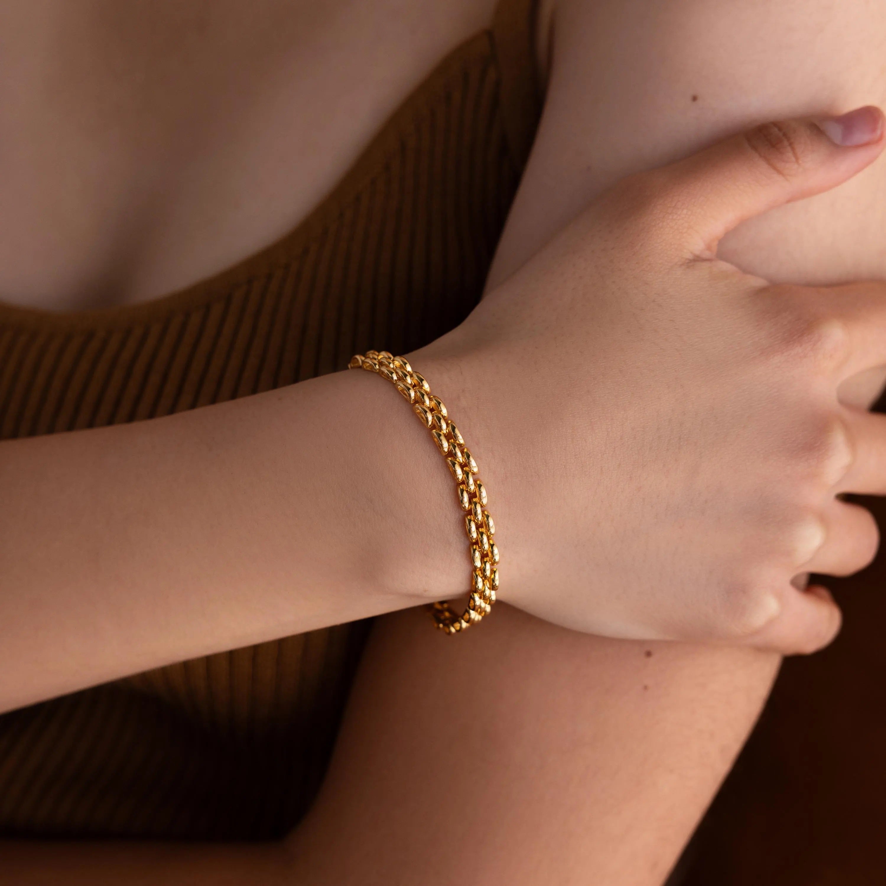 A person wearing a striking Strap Bracelet on their wrist, dressed in a brown sleeveless top.