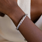 Silver North Star Diamond Bangle on women's wrist. The bangle is a dome shaped and features multiple North Star with Diamond CZ designs dotted around the bangle.
