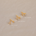 The Booker Diamond Studs Set features three pairs of lightweight gold earrings in small, medium, and large sizes on a light beige background—ideal for everyday wear.