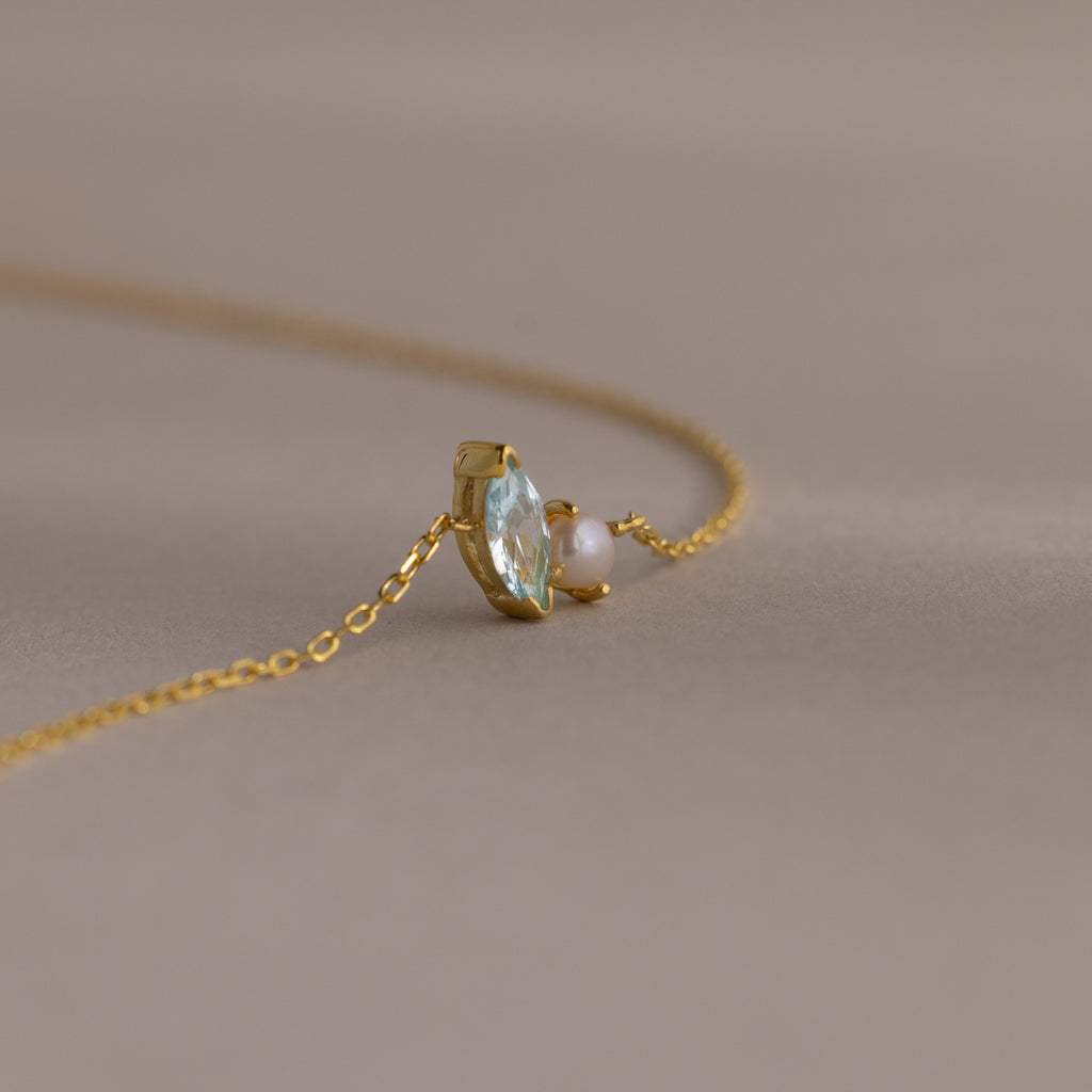 The Marquise Birthstone & Pearl Bracelet features a clear gemstone and small pearl—an elegant piece on a delicate chain, perfect as a thoughtful gift for someone special.
