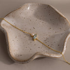 The Marquise Aquamarine & Pearl Bracelet, an elegant gift for someone special, is beautifully displayed on a speckled, wavy ceramic dish.