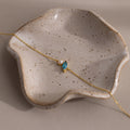 The Marquise Blue Zircon & Pearl Bracelet, featuring a blue gem and pearl, is displayed on a speckled wavy ceramic dish—a perfect gift for someone special.