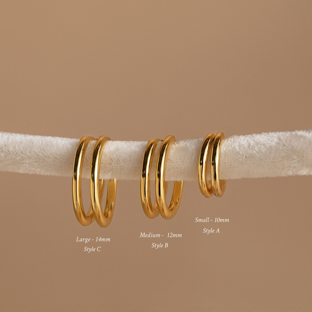 The Mini Bold Hoops Set features three pairs of classic hoop earrings in small, medium, and large sizes on a white textured rod—a striking addition to any Hoop Earrings Collection.