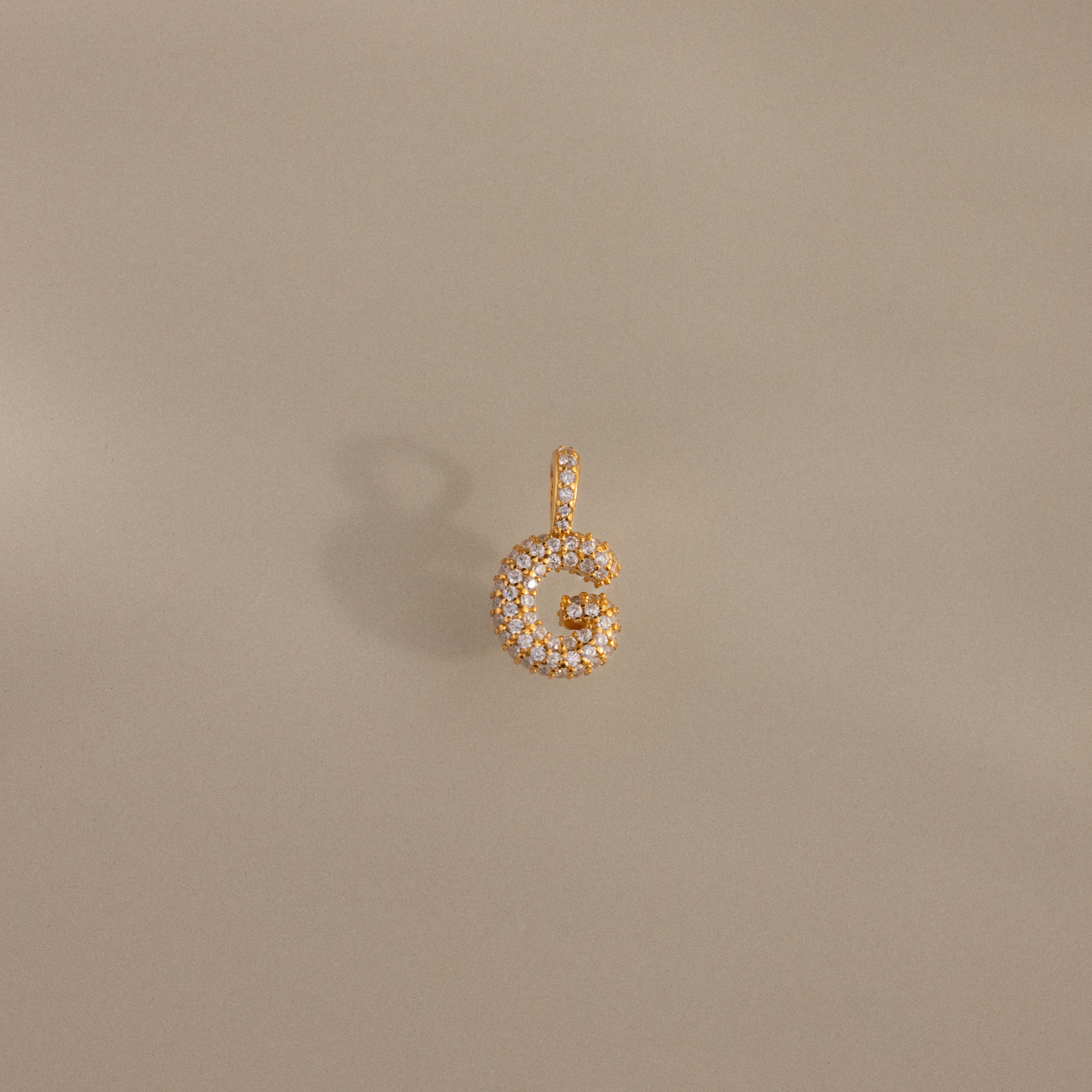 The Pave Bubble Letter Charm is a gold pendant shaped as the letter G with diamond-studded lettering in a bubble style, shown on a neutral background.
