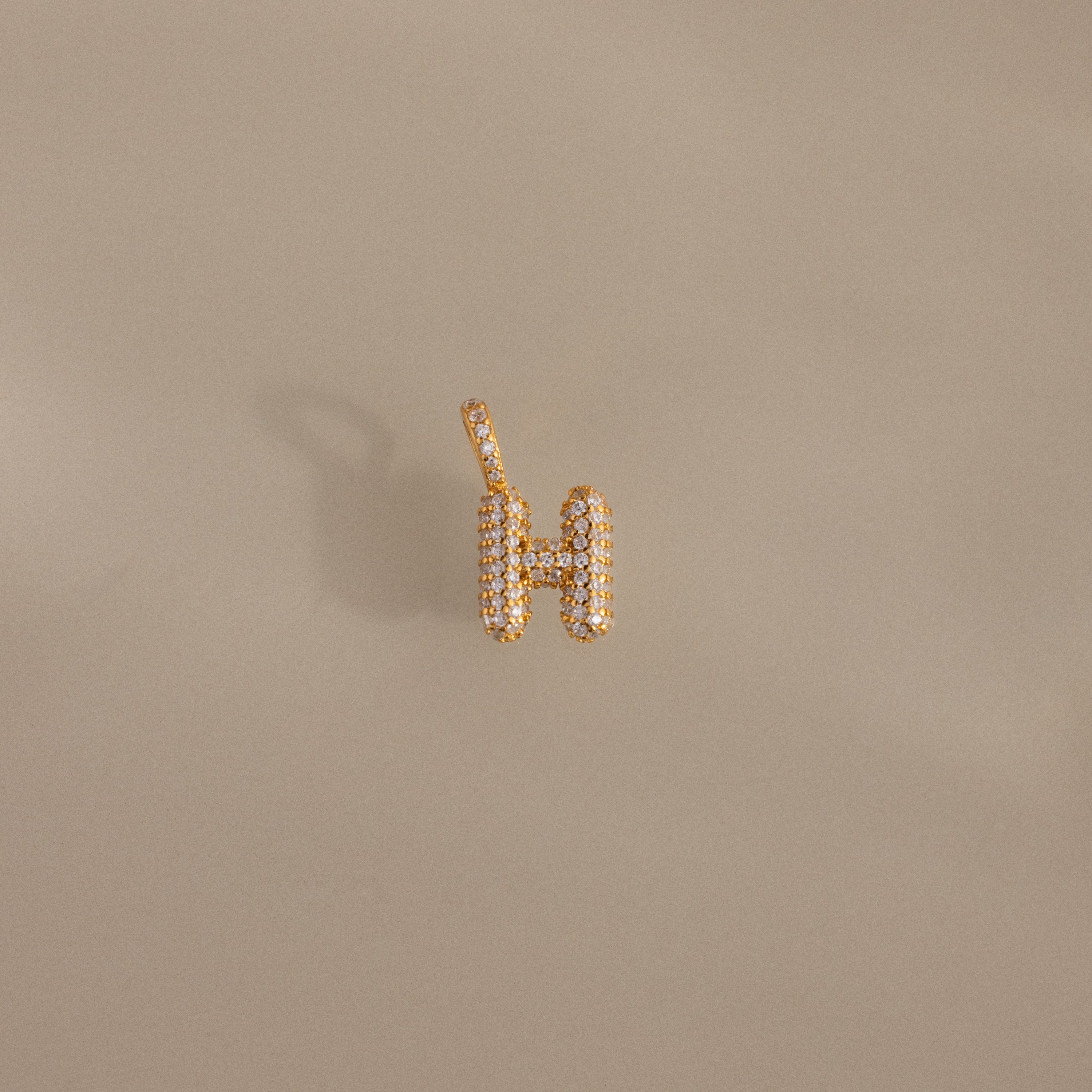 Pave Bubble Letter Charm featuring a gold "H" pendant with diamond-studded lettering, shown on a neutral beige background.