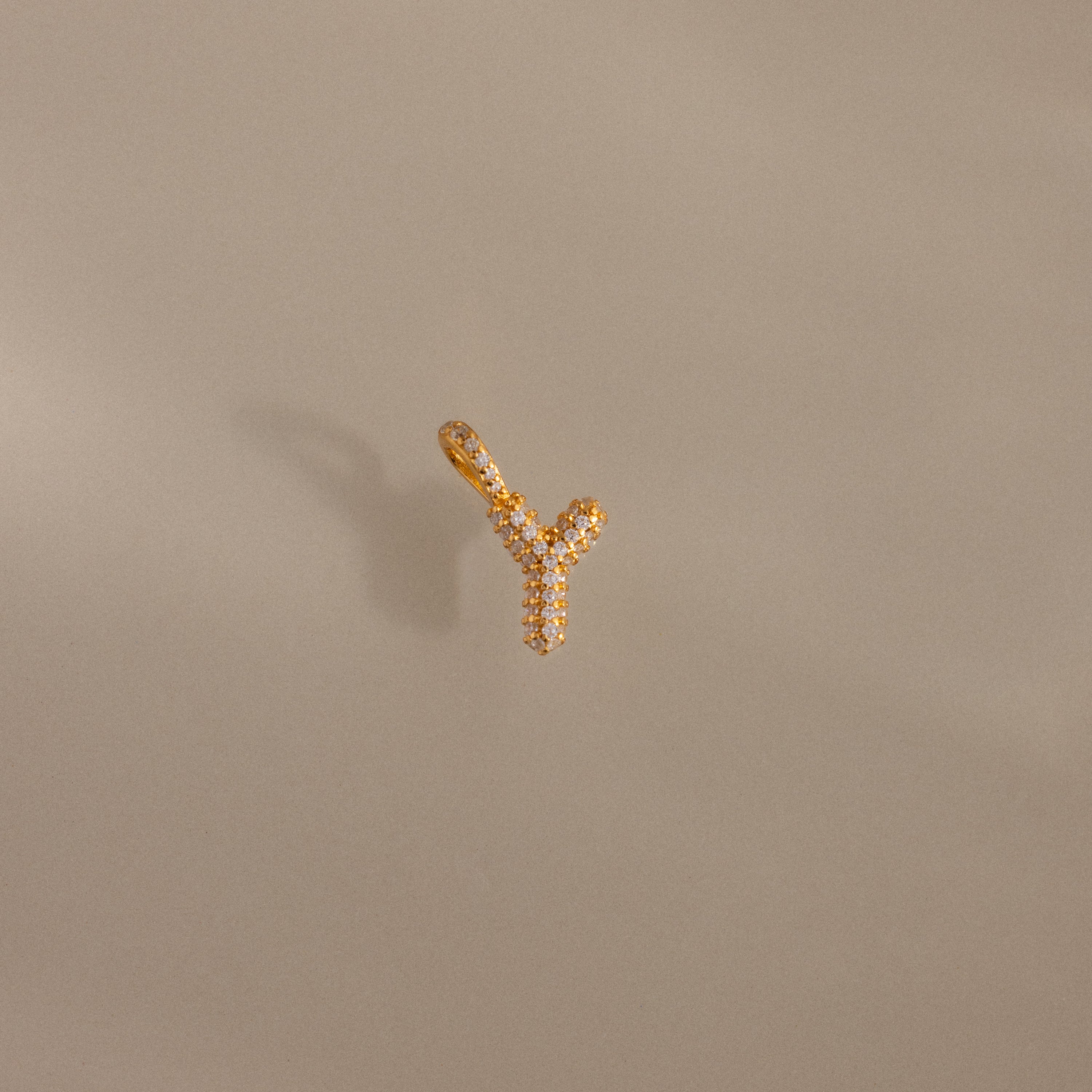 The Pave Bubble Letter Charm, shaped like the letter Y and adorned with diamond-studded pave stones, is displayed on a beige background.