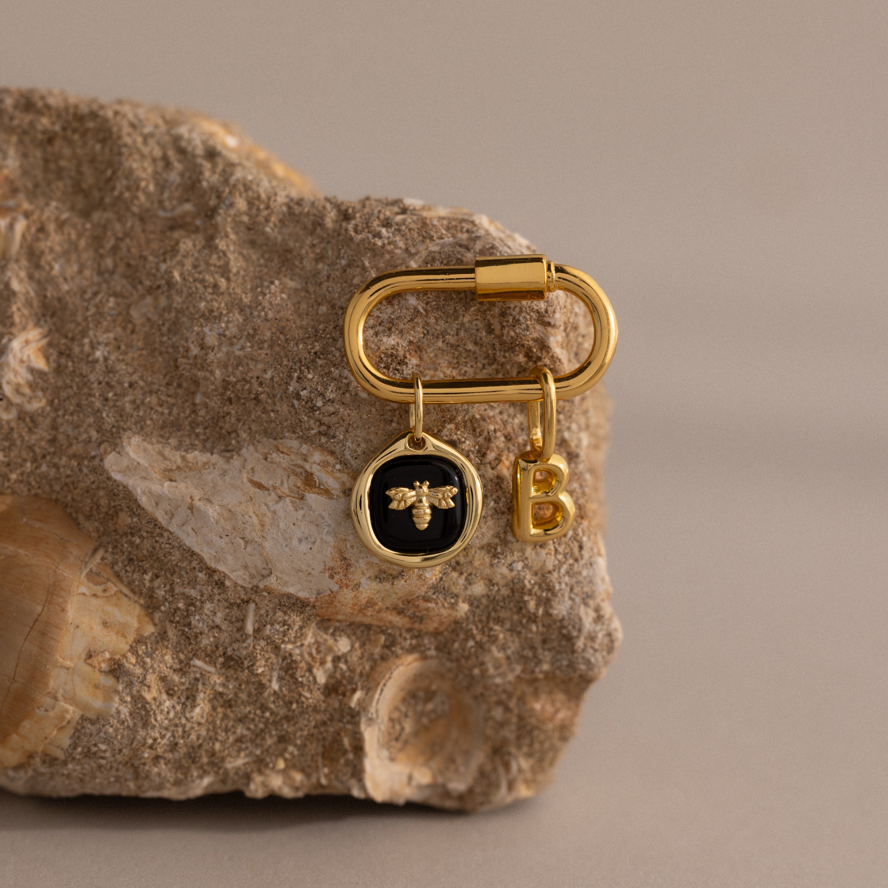 Onyx Honeybee Charm in 18K Gold keyring, displayed on a textured rock with shell fossils—ideal for nature lovers or as a personalised gift featuring both bee and initial B charms.