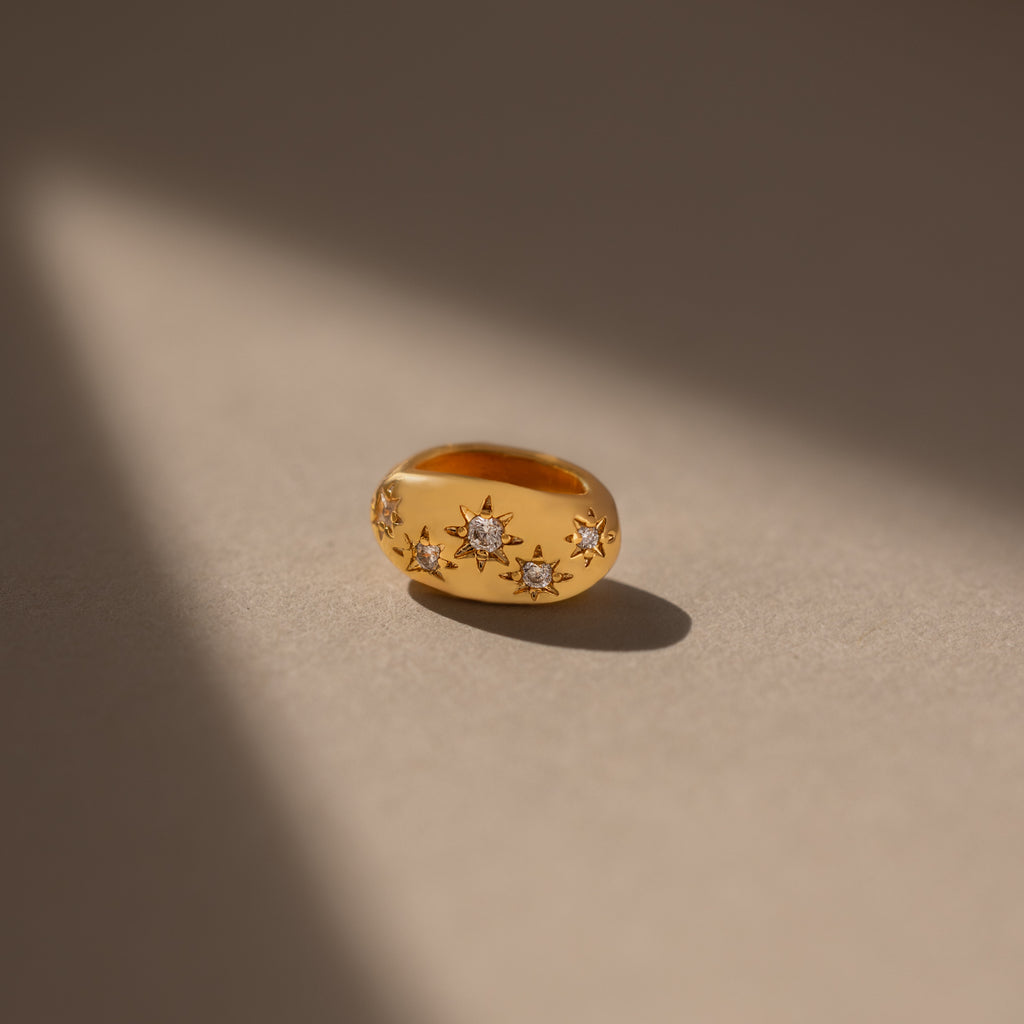 The Sprinkle Diamond Dome Charm in 18K Gold features starburst-set stones and star-shaped diamond accents, beautifully illuminated on a neutral background—a stunning addition to any charm stack.