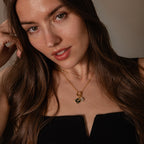 Woman with long brown hair wearing a black top and the Onyx Hummingbird Charm in Silver, gazing into the camera with elegant style—an ideal look to showcase this striking silver charm.