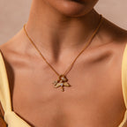 A woman in a yellow top wears the Bold Pave Dome Charm gold necklace—its winged pendant adds eye-catching elegance, perfect for elevating your product description.