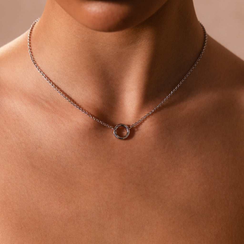 A person wears the Cable Circle Charm Necklace in Silver, featuring a simple circular pendant that creates a subtle statement around their neck.