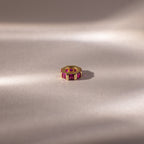 The Infinity Princess Ruby Charm is showcased on a soft, neutral surface with gentle lighting.