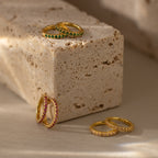 Diamond Clicker Huggies shine beside gold rings with red, green, and clear stones—perfect everyday earrings for adding a colorful touch.