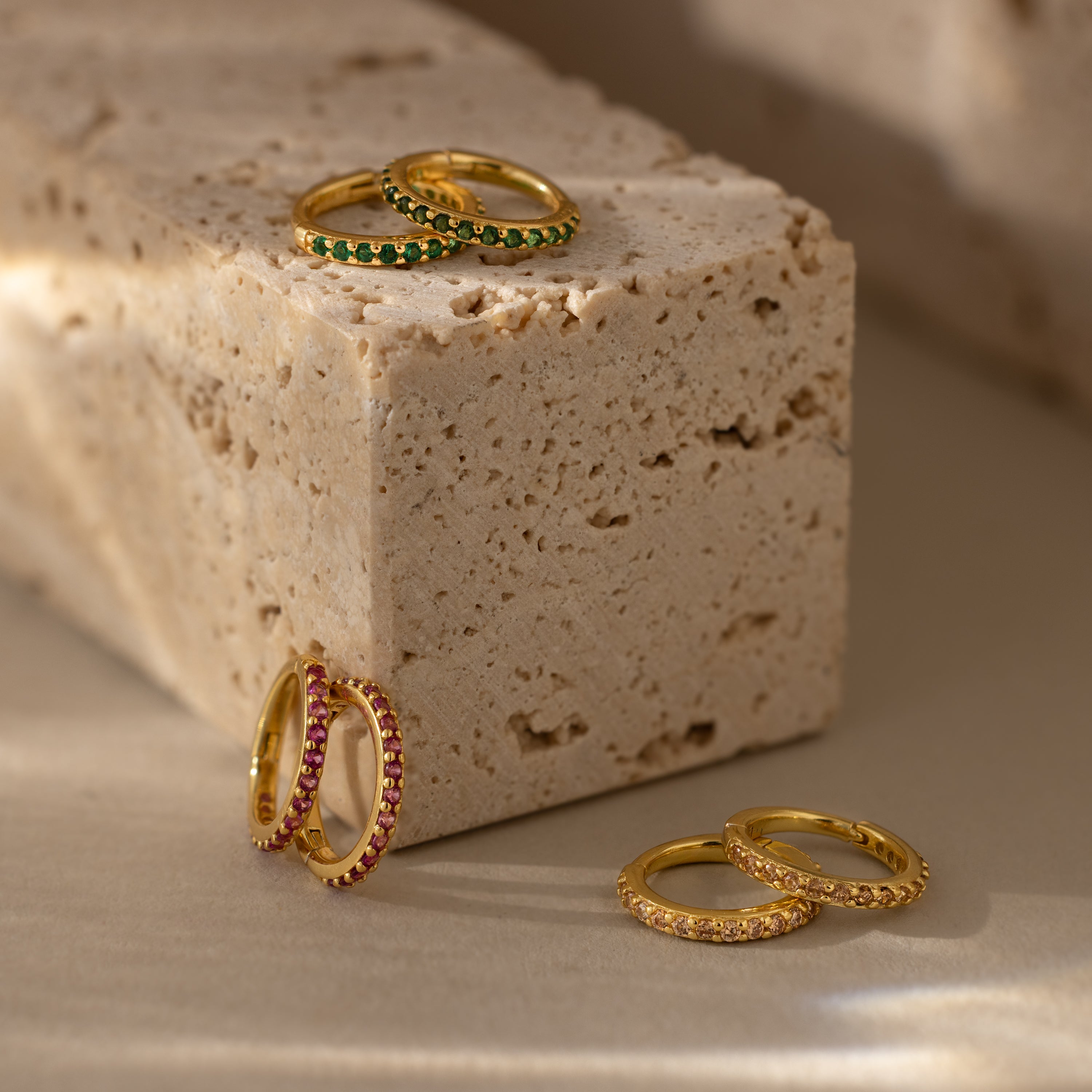 Diamond Clicker Huggies shine beside gold rings with red, green, and clear stones—perfect everyday earrings for adding a colorful touch.