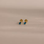 Teardrop Blue Zircon Flatback Studs: gold earrings featuring teardrop-shaped blue zircon gemstones, perfect for elegant birthstone jewelry lovers. Displayed on a neutral background.