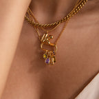 Close-up of layered gold necklaces with colorful gemstone pendants, featuring a sparkling Infinity Princess Topaz Charm resting gracefully on a person's neck.