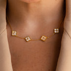 A close-up of a person wearing the Gemstone Clover Letter Necklace, featuring five white charms crafted in 925 sterling silver, styled elegantly with a beige blazer.