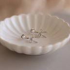 Pearl & Bow Ear Jackets in Sterling Silver shown with pearl studs on a white scalloped dish.
