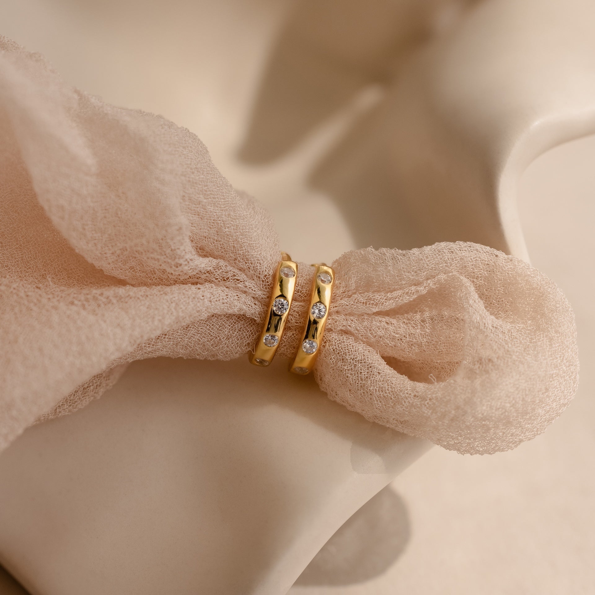 Mini Diamond Sprinkle Huggies in 18K Gold, featuring small diamonds, displayed on soft beige fabric.