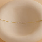 Heart Link Chain Necklace in 18K Gold displayed on a smooth, round, off-white dish with a soft beige background.