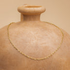 The Heart Link Chain Necklace, with its interlocking hearts, is displayed on a smooth clay vase against a beige background, adding a subtle touch of romance.