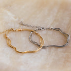 Two double-stranded bracelets—one gold, one silver—make a chic layered statement on marble, ideal for minimal jewelry lovers or pairing with your Triple Snake Chain Bracelet in White Gold.