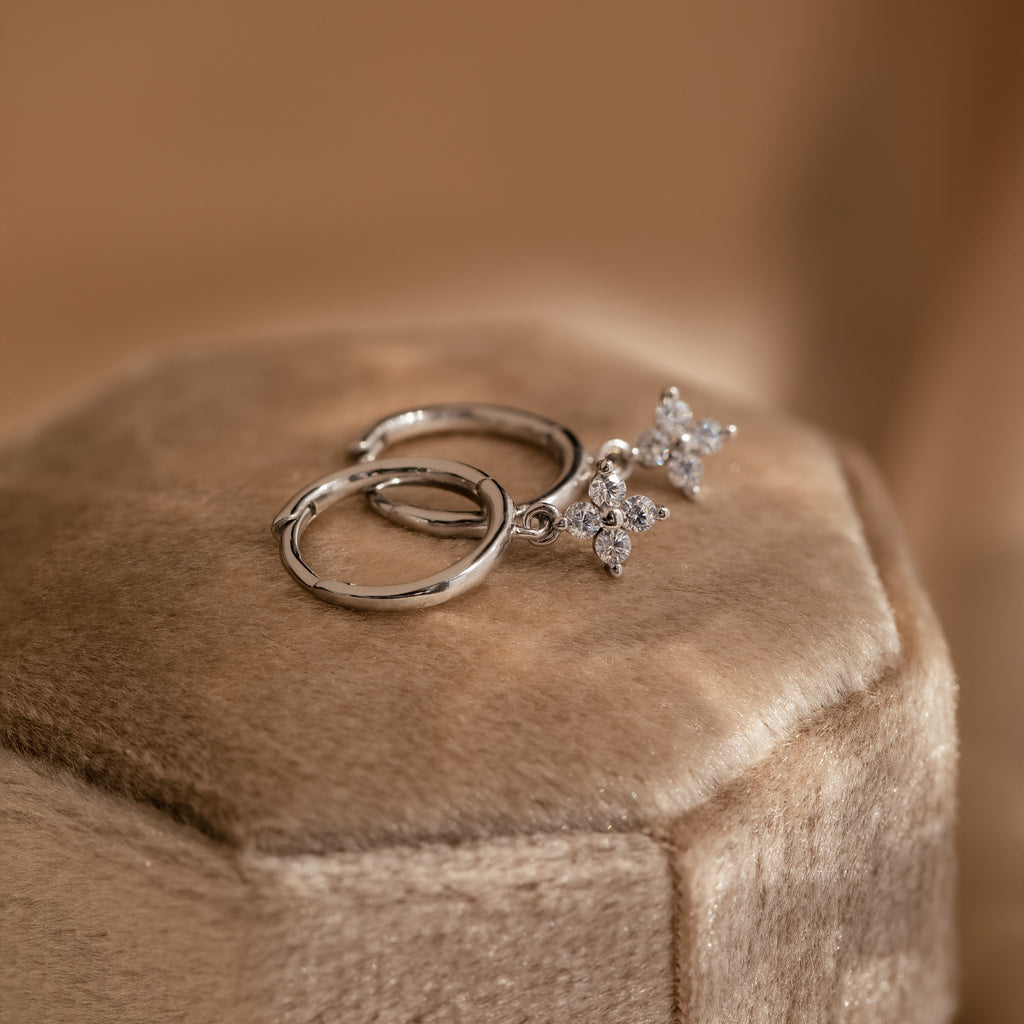 A close-up view of the silver Diamond Flower Huggie laid on a velvet jewelry box