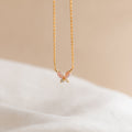 Pink Opal Butterfly Necklace in 18K Gold, featuring a delicate butterfly charm, photographed on a soft beige and white background.